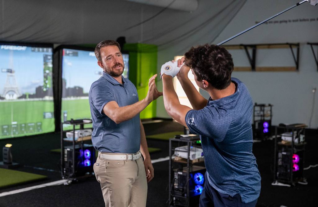 Luke Benoit talking a player through a swing change on the RYP Academy simulator floor